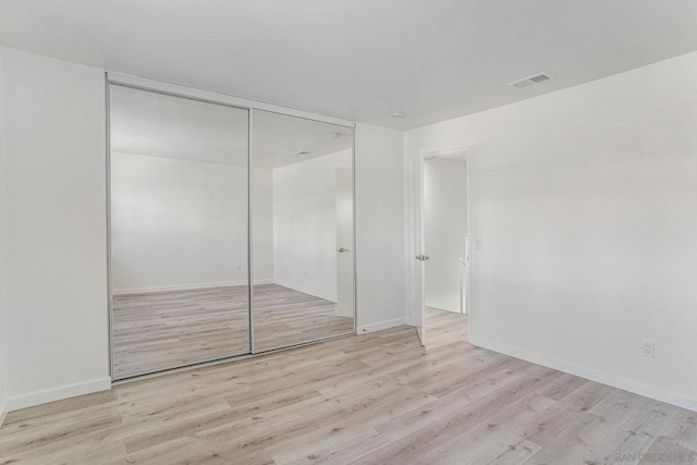 unfurnished bedroom featuring light hardwood / wood-style flooring and a closet