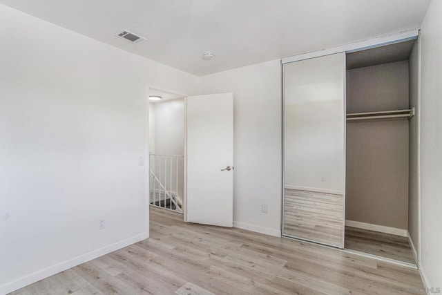 unfurnished bedroom with light hardwood / wood-style floors and a closet