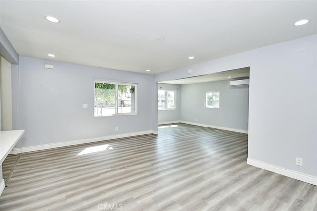 empty room featuring light wood-type flooring and a wall mounted AC