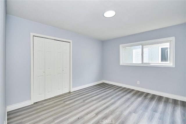 unfurnished bedroom with light hardwood / wood-style flooring and a closet