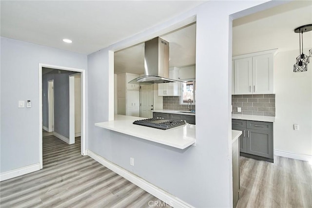 kitchen with sink, hanging light fixtures, light hardwood / wood-style floors, gray cabinets, and island range hood