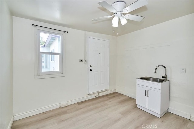 clothes washing area with light hardwood / wood-style floors, ceiling fan, and sink