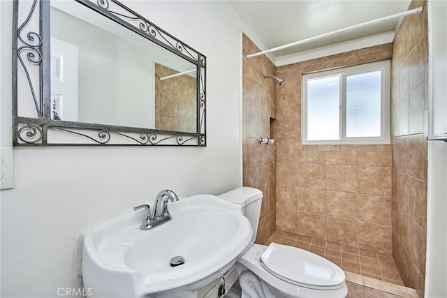 bathroom featuring tiled shower, toilet, and sink