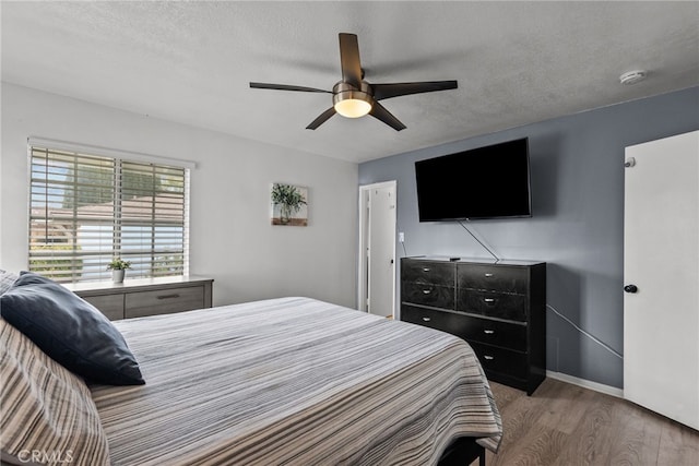 bedroom featuring hardwood / wood-style floors, ceiling fan, and a textured ceiling