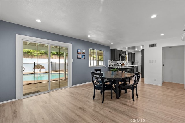 dining room with light wood-type flooring and a textured ceiling