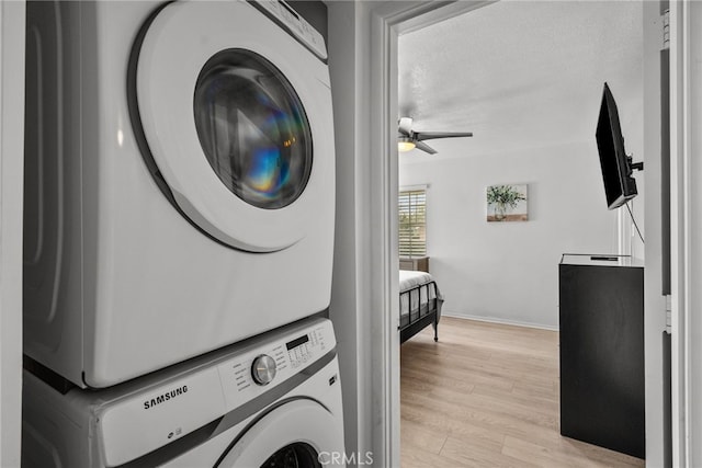 washroom with ceiling fan, stacked washing maching and dryer, and light hardwood / wood-style floors