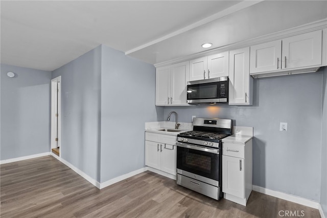 kitchen with hardwood / wood-style flooring, sink, white cabinets, and appliances with stainless steel finishes