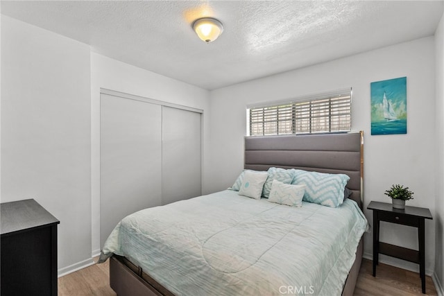 bedroom featuring hardwood / wood-style flooring, a textured ceiling, and a closet