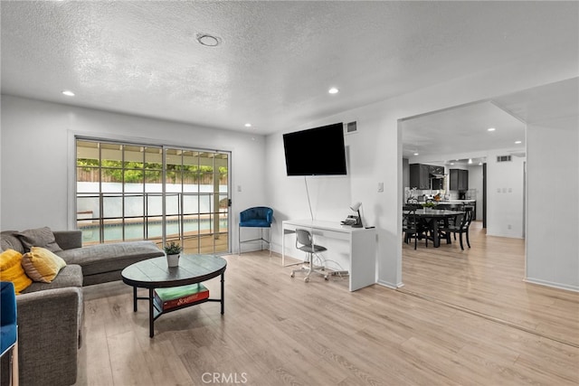 living room featuring light hardwood / wood-style flooring and a textured ceiling