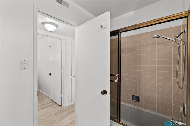 bathroom with enclosed tub / shower combo and wood-type flooring