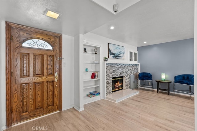 entryway featuring a textured ceiling, light hardwood / wood-style floors, and a fireplace