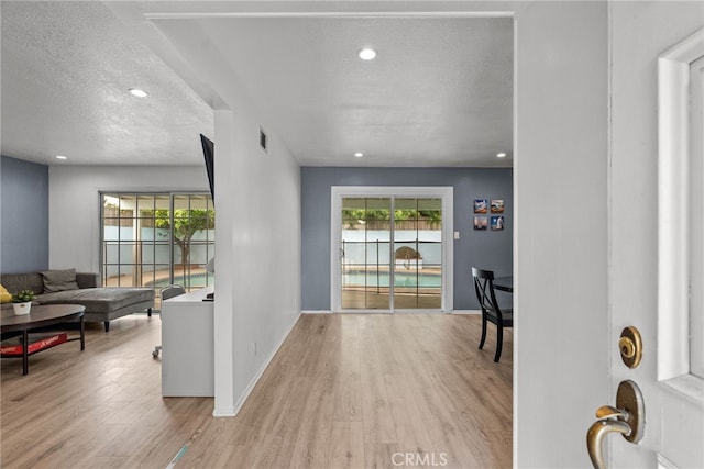 corridor featuring light hardwood / wood-style flooring and a textured ceiling