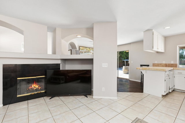 interior space featuring white cabinets, kitchen peninsula, and light tile patterned floors