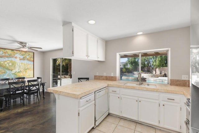 kitchen featuring white dishwasher, kitchen peninsula, white cabinetry, and sink