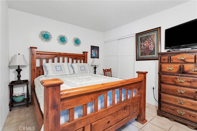 bedroom with a textured ceiling, light tile patterned floors, and a closet