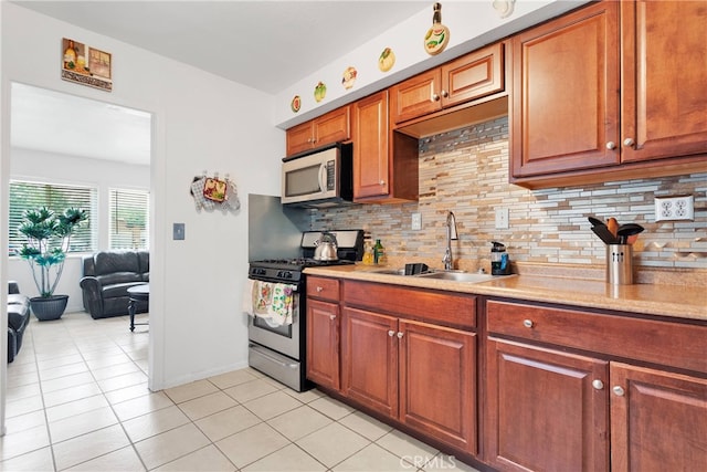 kitchen with appliances with stainless steel finishes, sink, light tile patterned floors, and tasteful backsplash