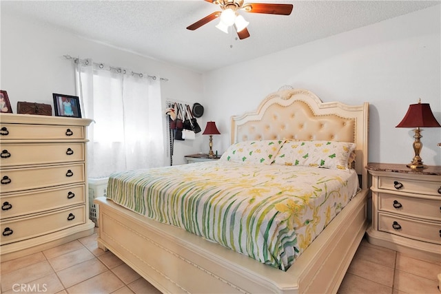 bedroom with ceiling fan, a textured ceiling, and light tile patterned floors