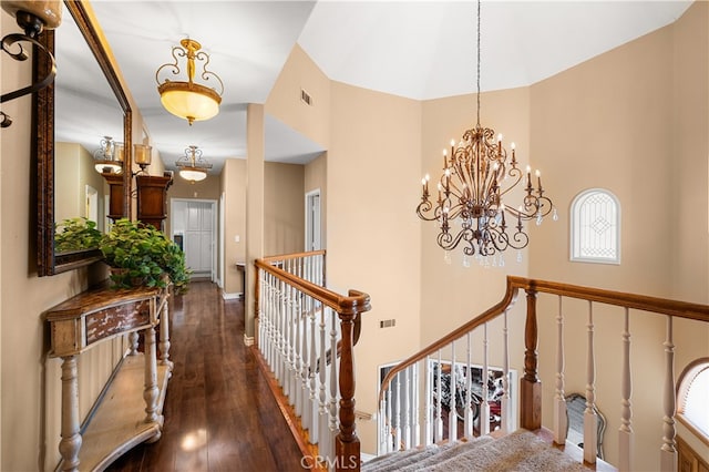 hall with a towering ceiling, an inviting chandelier, and dark hardwood / wood-style floors