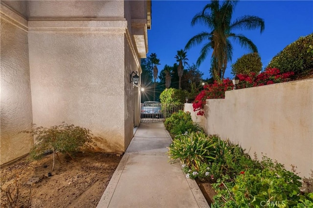 view of side of property featuring fence, a gate, and stucco siding