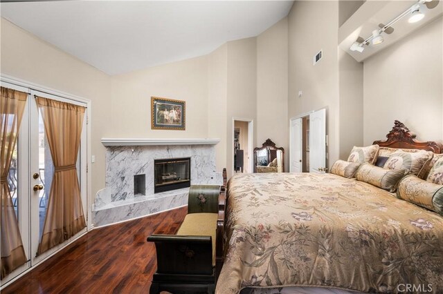 bedroom with high vaulted ceiling, visible vents, wood finished floors, and a high end fireplace