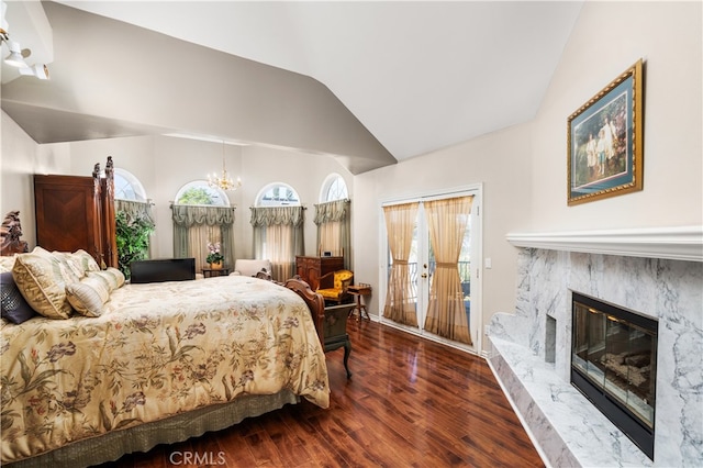 bedroom featuring access to outside, a fireplace, lofted ceiling, dark wood-type flooring, and a chandelier