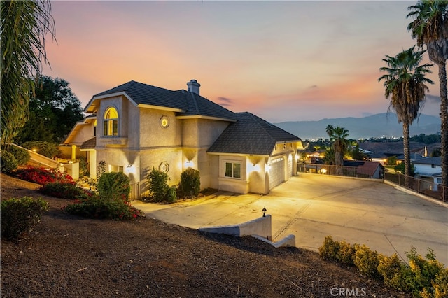 property exterior at dusk with a garage and a mountain view