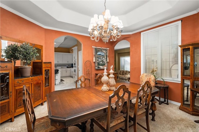 dining area featuring arched walkways, an inviting chandelier, light carpet, and a raised ceiling