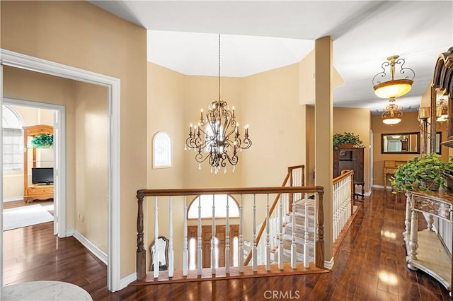 hall with baseboards, hardwood / wood-style flooring, and a notable chandelier