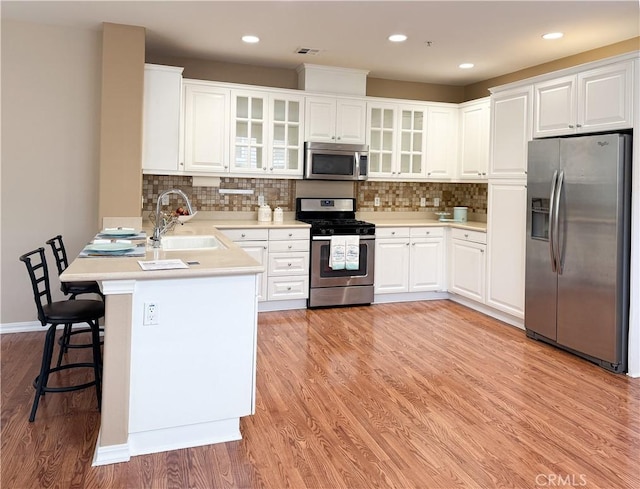 kitchen with white cabinets, kitchen peninsula, sink, and stainless steel appliances