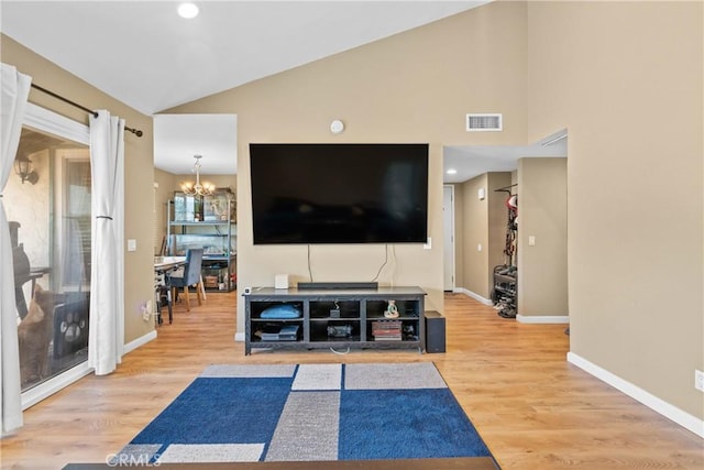 living room featuring high vaulted ceiling, wood-type flooring, and an inviting chandelier