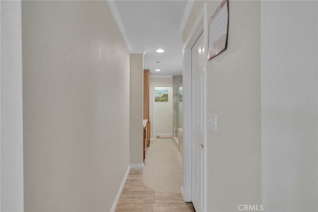 corridor with light hardwood / wood-style flooring and ornamental molding