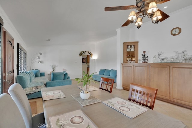 tiled dining space with ceiling fan and ornamental molding