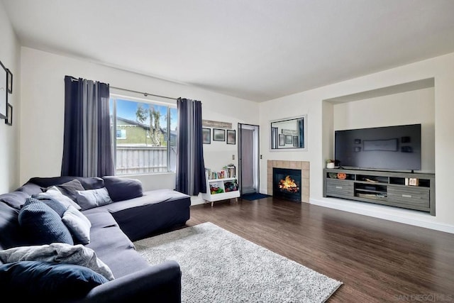 living room with a tile fireplace and dark hardwood / wood-style flooring