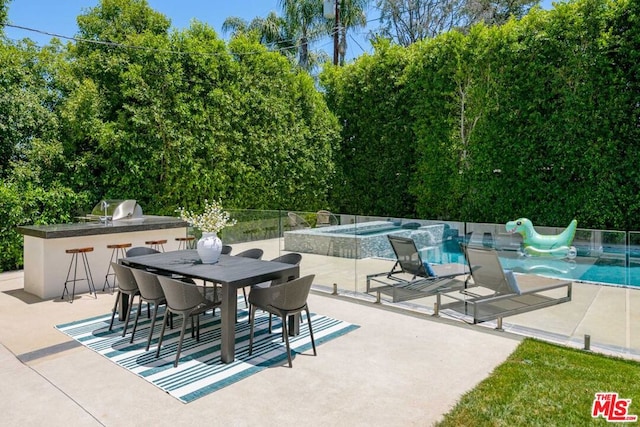 view of patio featuring a pool with hot tub, area for grilling, exterior kitchen, and exterior bar