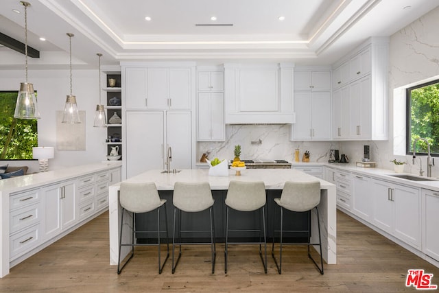 kitchen with a kitchen breakfast bar, white cabinetry, sink, and a center island with sink