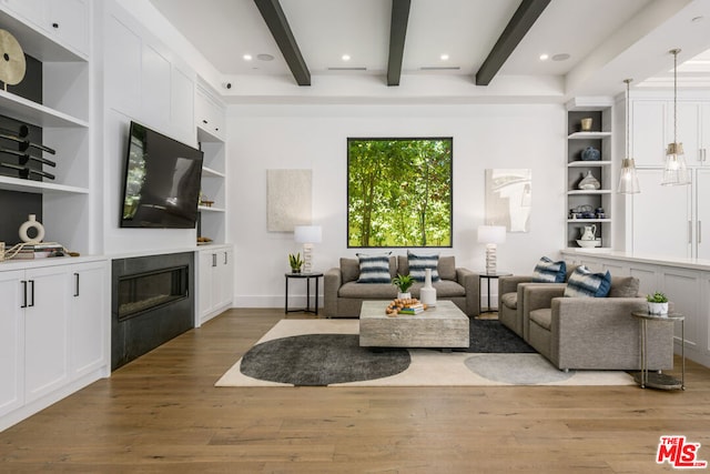 living room featuring beamed ceiling, built in shelves, and light hardwood / wood-style flooring