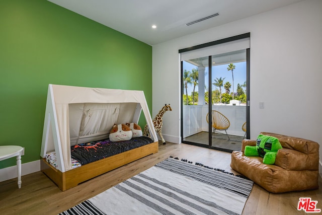 bedroom with hardwood / wood-style floors and access to outside