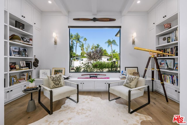 living area featuring beam ceiling, a wealth of natural light, and light hardwood / wood-style floors