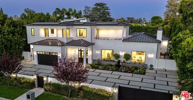 view of front of house with a garage, a balcony, and solar panels