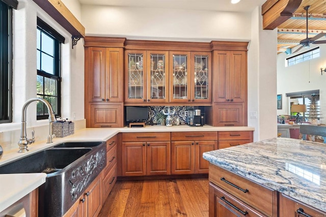 kitchen with sink, beam ceiling, light hardwood / wood-style flooring, and light stone countertops