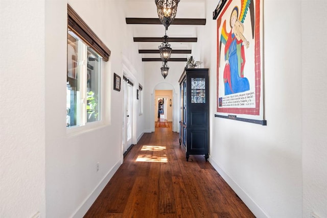 corridor with beam ceiling, a chandelier, and dark hardwood / wood-style flooring