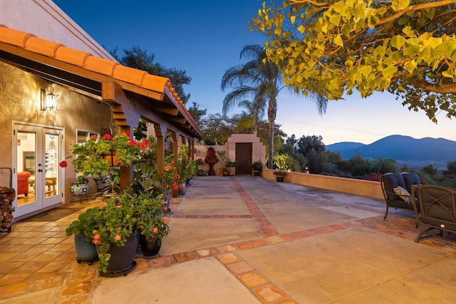 patio terrace at dusk featuring a mountain view and french doors