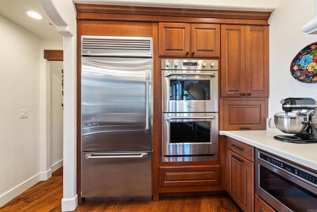 kitchen with appliances with stainless steel finishes and hardwood / wood-style floors