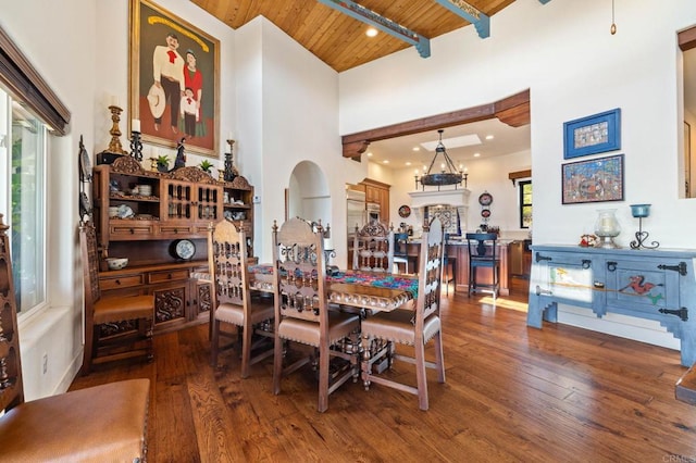 dining room featuring beam ceiling, a towering ceiling, dark hardwood / wood-style flooring, and wooden ceiling