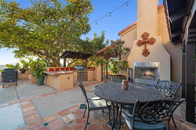 view of patio / terrace featuring a grill, sink, an outdoor fireplace, and exterior kitchen