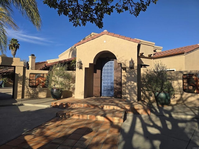 mediterranean / spanish-style house featuring a patio, a tiled roof, and stucco siding