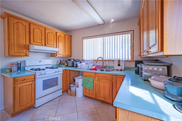 kitchen with light tile patterned floors, sink, and white gas stove