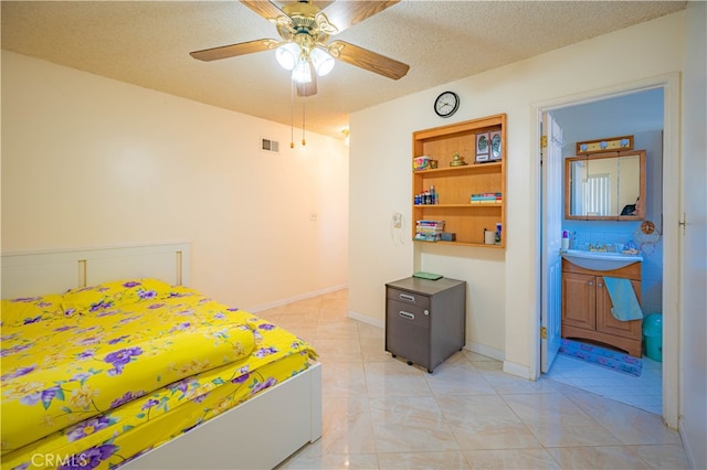 bedroom featuring ceiling fan, a textured ceiling, ensuite bath, and sink