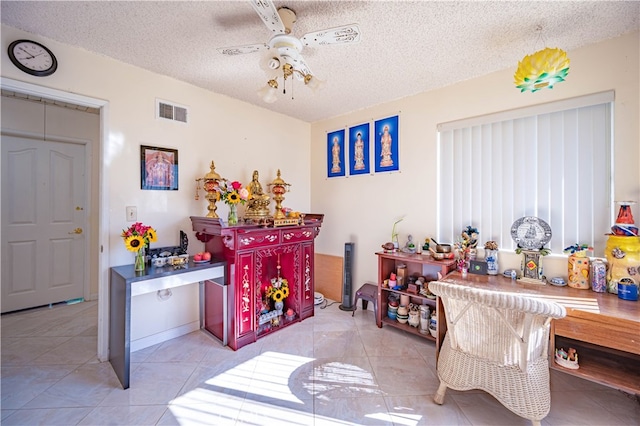 interior space featuring ceiling fan, a textured ceiling, and light tile patterned floors