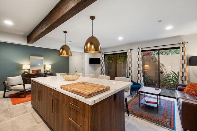 kitchen with beam ceiling, a center island, dark brown cabinets, and pendant lighting